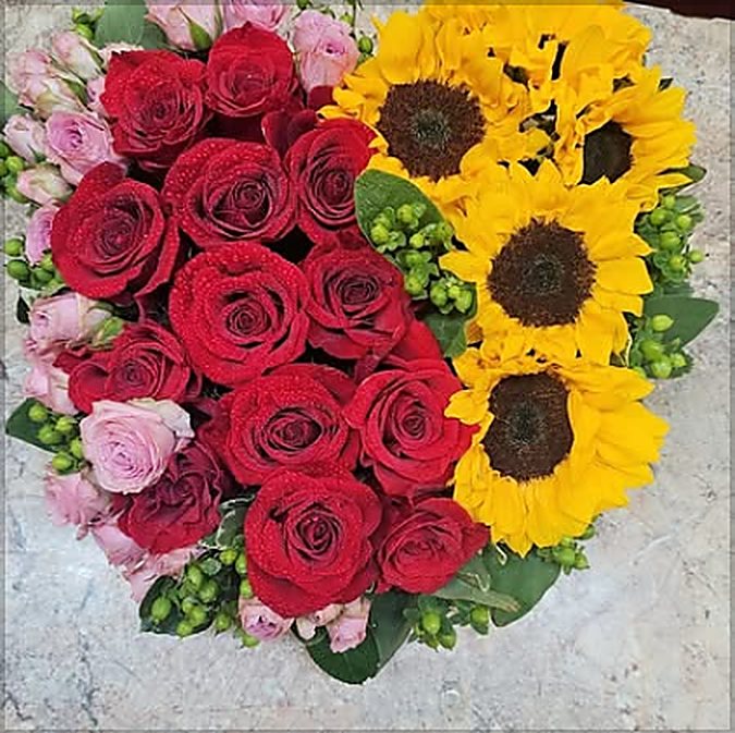 Heart shaped arrangement of red roses and sunflowers